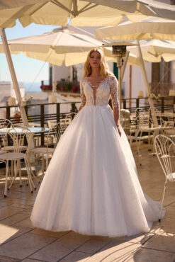 Ball gown wedding dress with beaded feather-motif illusion bodice, 3/4 sleeves, and glitter tulle skirt.