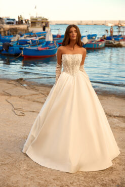 Ball gown wedding dress with strapless beaded corset bodice, full ivory satin skirt, and separate long lace sleeves.